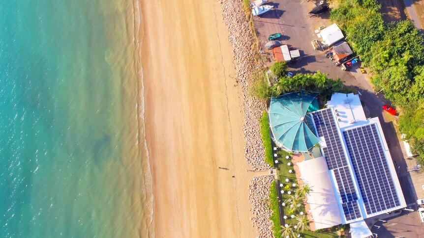An aerial image of a beachside boat club with a pool in its back courtyard.