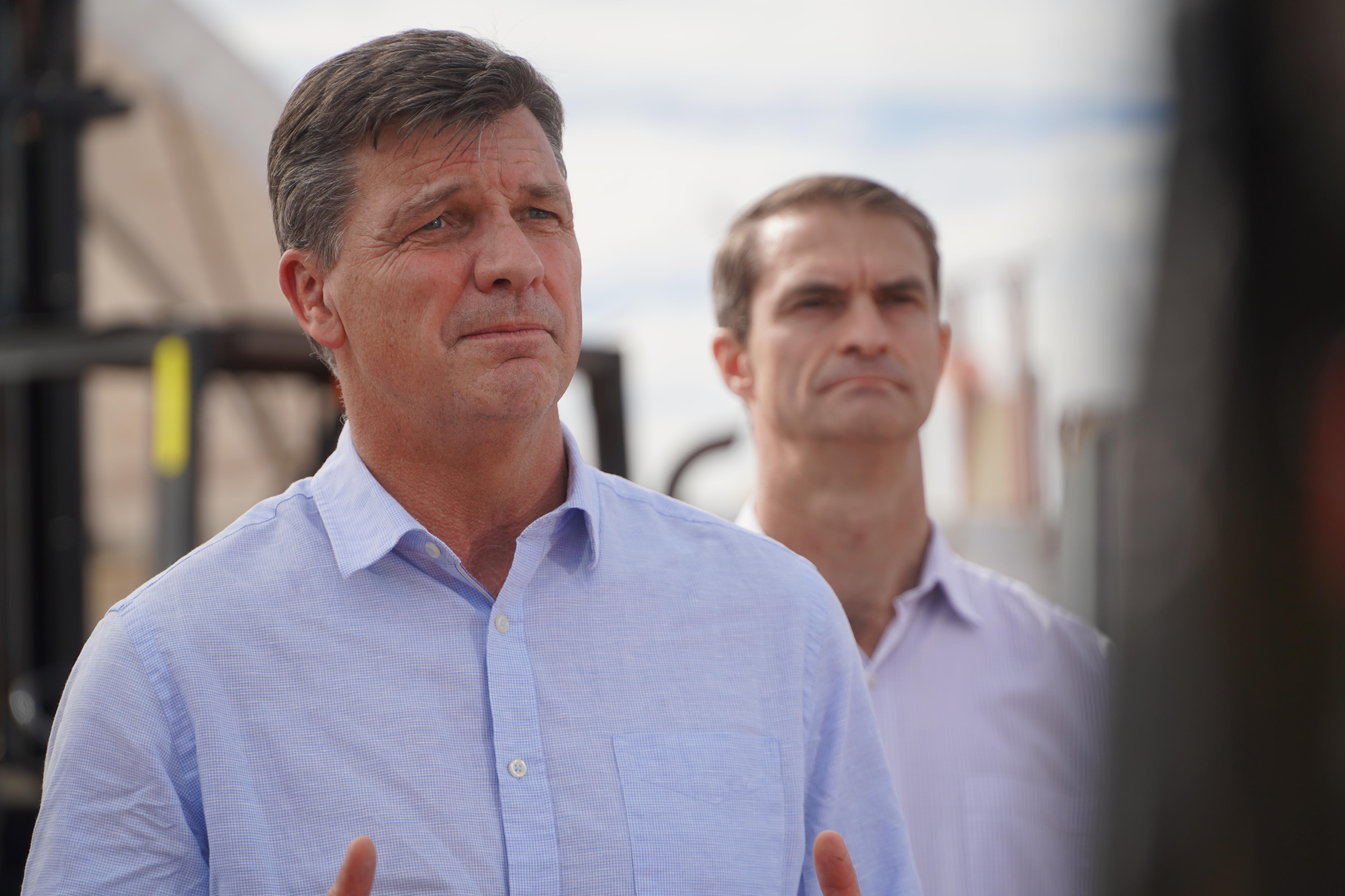 A man in a button up blue shirt with grey hair looks to the right