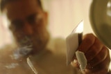A man prepares lines of cocaine on a table.