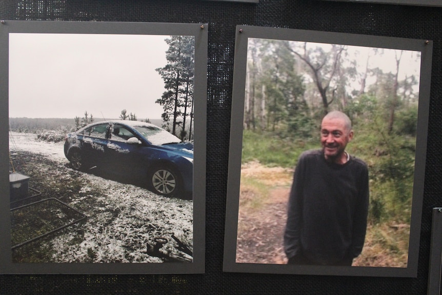 A photo of a car covered in snow and a skinny bald man in the bush. 