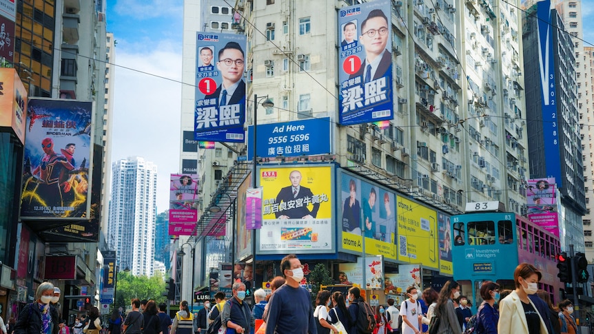 A crowded street in Hong Kong with election signs on the buildings above