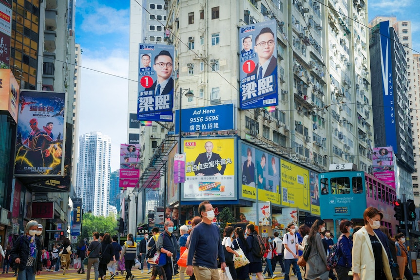 A crowded street in Hong Kong with election billboards on the buildings above