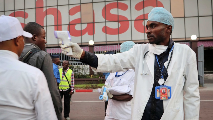 A health worker checks people's temperatures as they disembark a plane