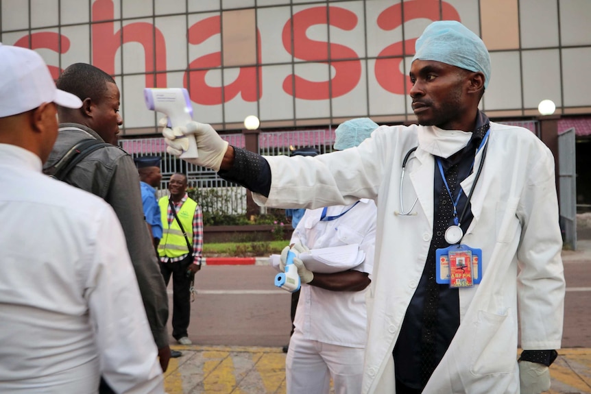 A health worker checks people's temperatures as they disembark a plane