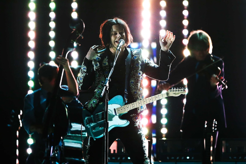 Jack White sings into a microphone on stage