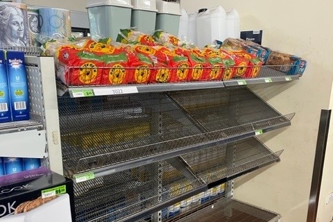 only one row of shelves is filled with packaged bread in a store