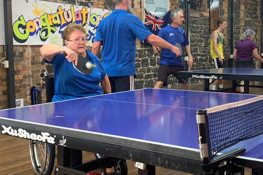 Woman in wheelchair playing table tennis.