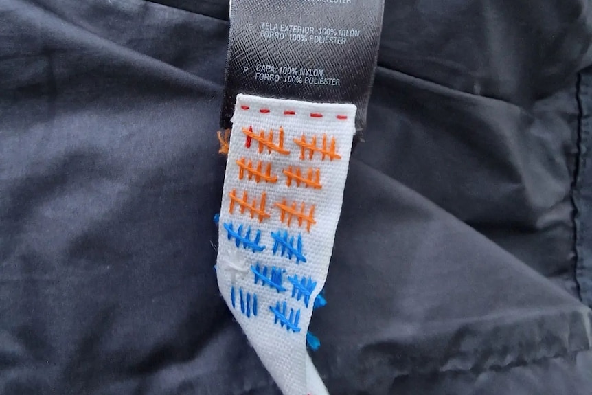 Hand stitches in various colours are marked on a clothing tag