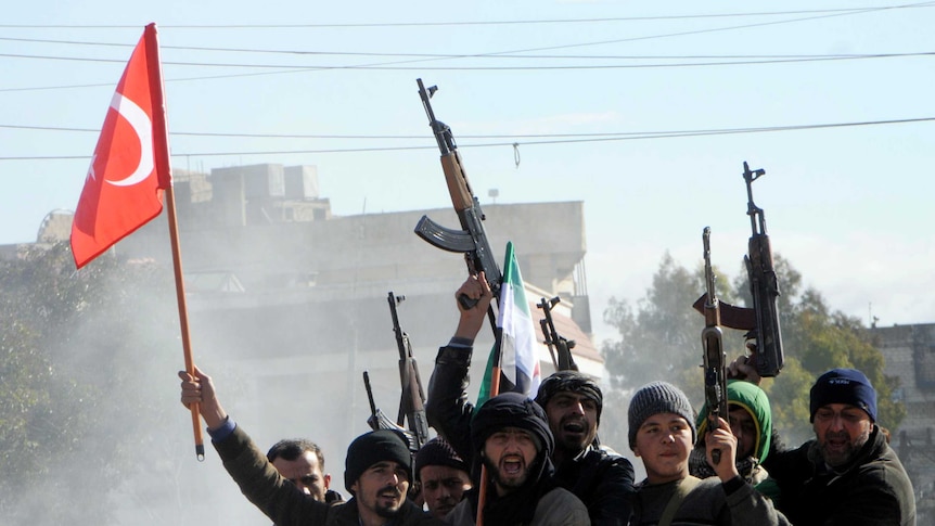 Turkey-backed Free Syrian Army fighters ride in the back of a pick-up truck holding guns and Turkish and Syrian rebel flags