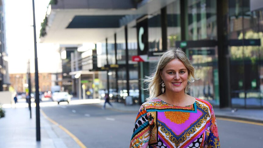 A woman in a colourful shirt standing in a street.