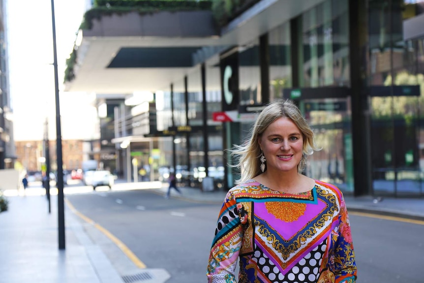 A woman in a colourful shirt standing in a street.