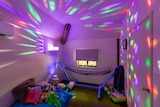 a dark room with bright lights, a hammock and toys.