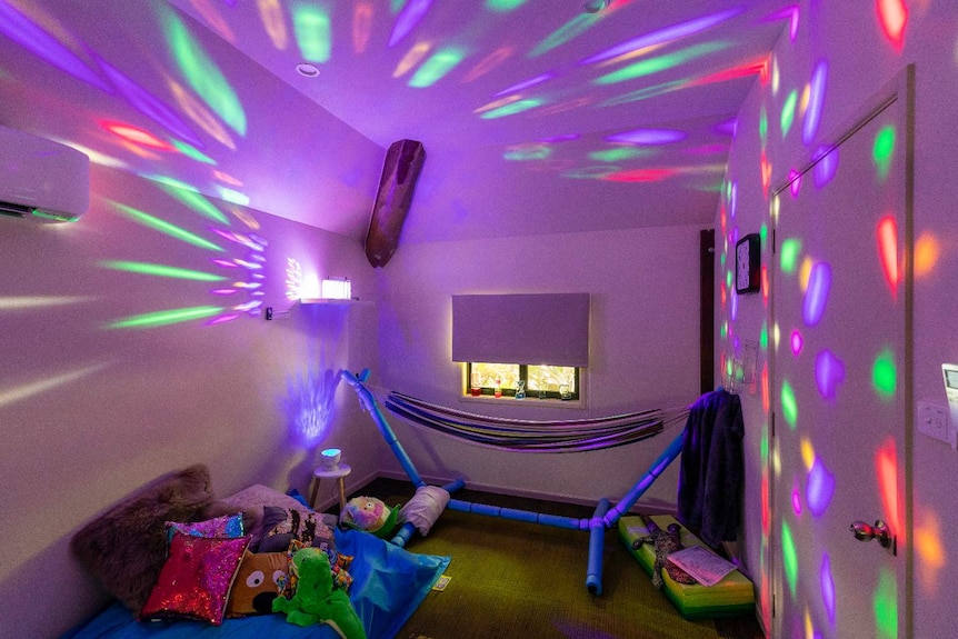 a dark room with bright lights, a hammock and toys.