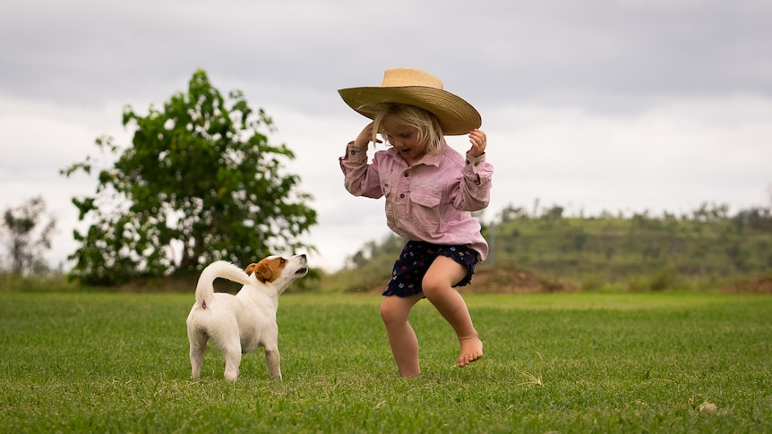 Photo of a child jumping up and down with a dog.