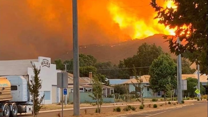 Orange flames can be seen rising over a mountain, from the main street in Walwa.