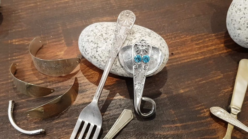 A fork lays next to an elephant with blue crystal eyes that's been made out of another fork.
