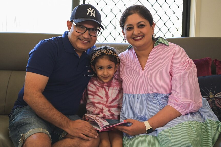 Dr Mohit Shahi, his wife Rachita Narula and daughter Eugenia sits on a couch in their Brisbane home