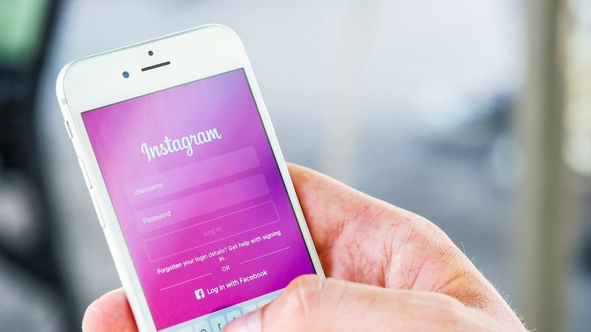 A hand holds a phone showing the login screen on instagram on a mobile phone
