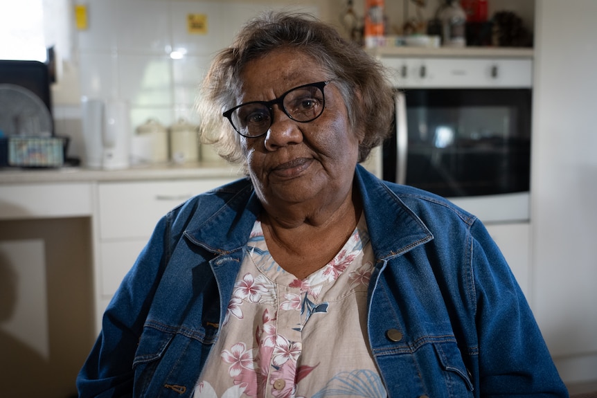 A woman with glasses sitting in a kitchen