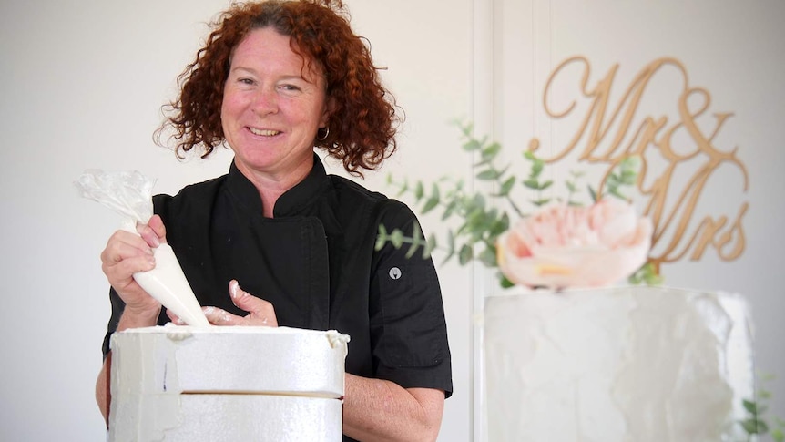 Baker Debra Magatelli in her kitchen, she is decorating a polystyrene block to look like a cake