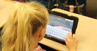 An image of a girl using a tablet at a desk.