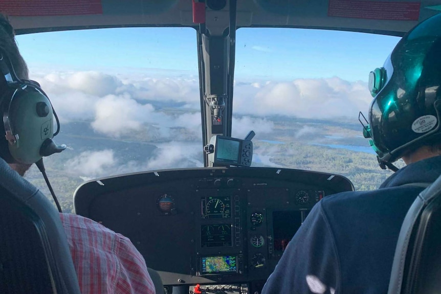 The view from behind a pilot as a helicopter approaches a lake