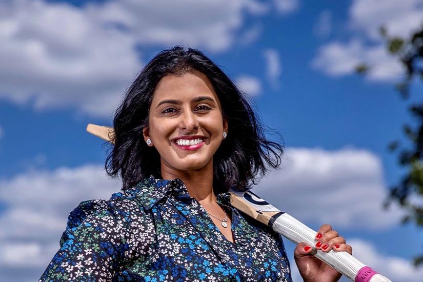 A portrait of Aish Ravi holding a cricket bat over her shoulder.