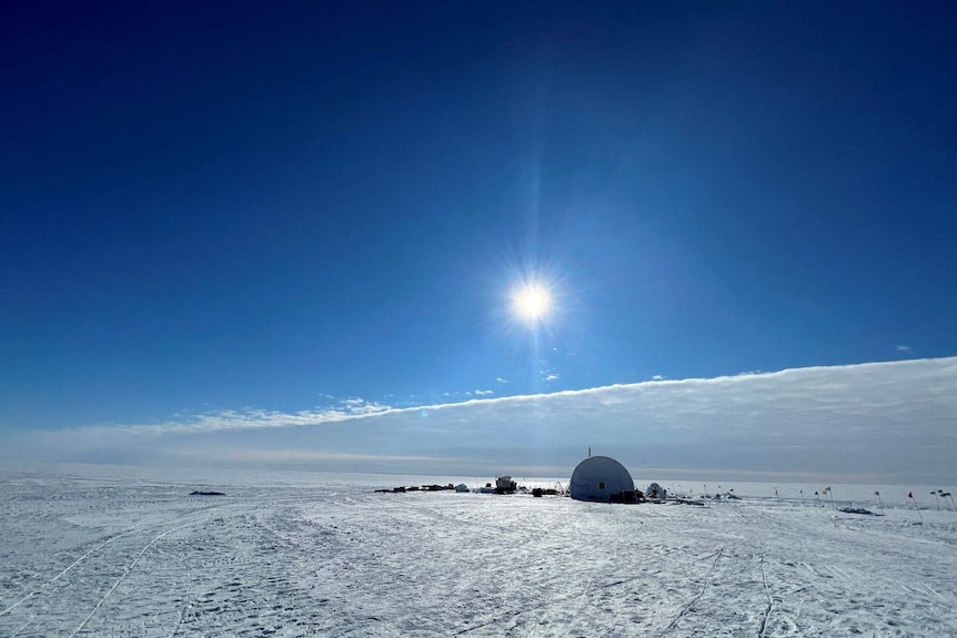 Ice and blue sky with tent in distance.