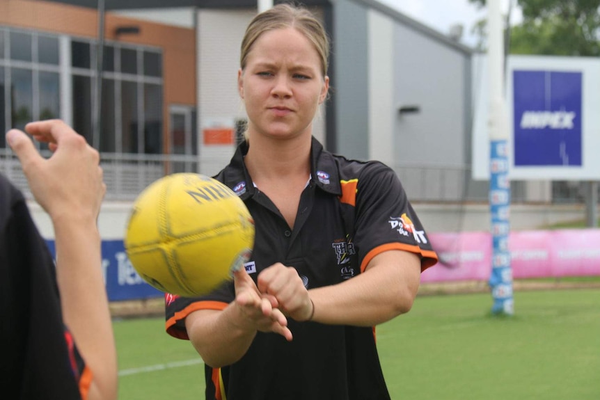 Ashley Fitzpatrick focusses as she handballs a football.