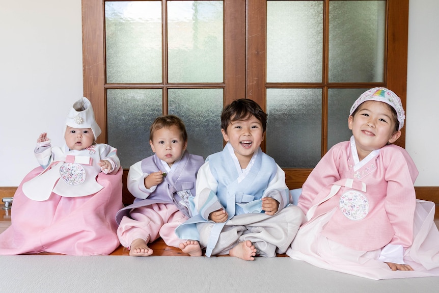 Esther's four young children grin in their hanboks, which are various pastel colours.