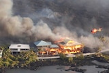 An aerial shot shows multi-storey houses on fire after being engulfed by lava.