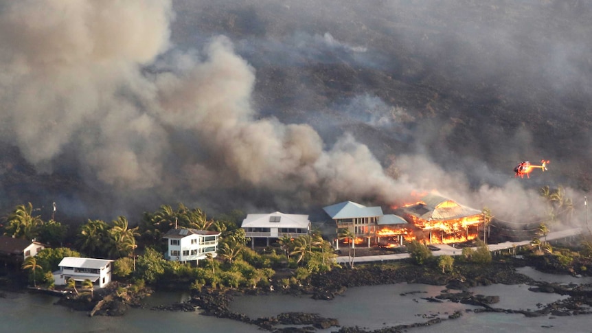 An aerial shot shows multi-storey houses on fire after being engulfed by lava.