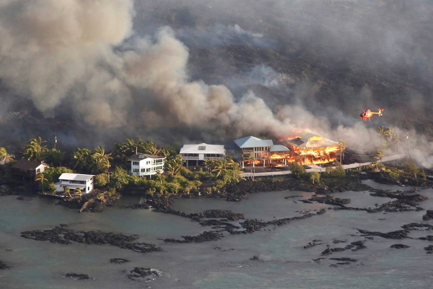 An aerial shot shows multi-storey houses on fire after being engulfed by lava.