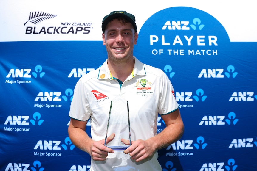 Cameron Green smiles while holding a small glass trophy
