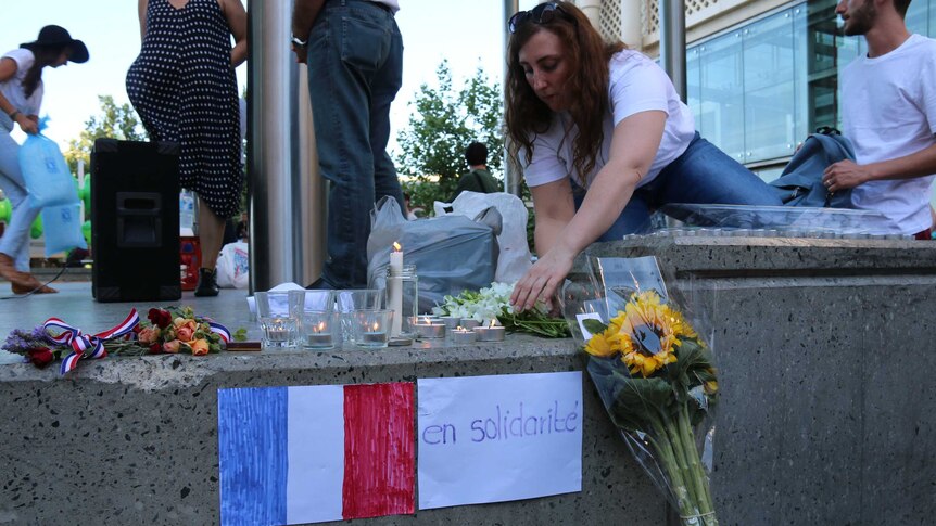 Flowers and candles alongside a sign representing solidarity with France.