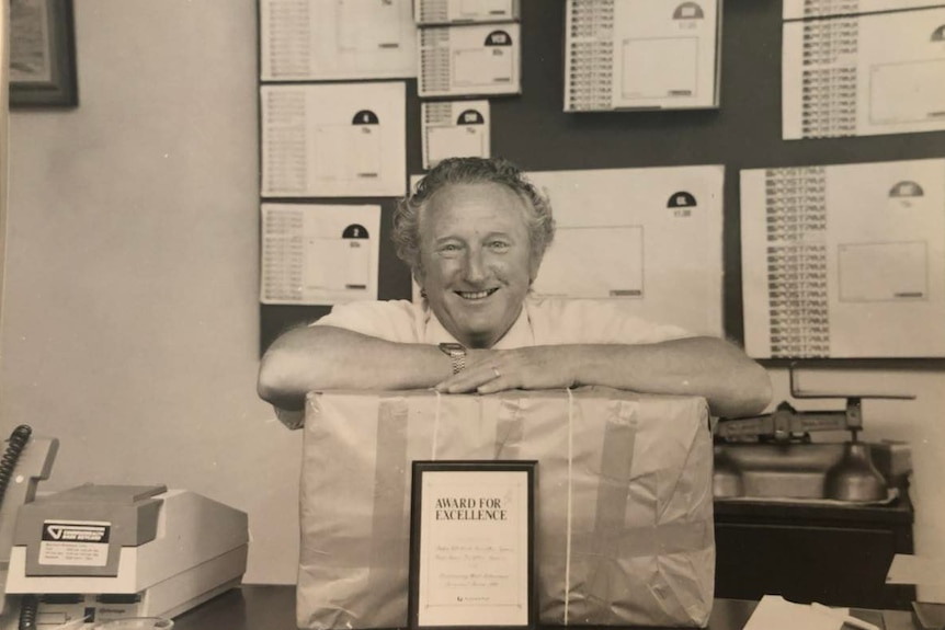 Black and white photo of Keith Austin with a parcel.