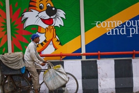An Indian commuter cycles past Comm Games banner (Getty Images: Daniel Berehulak)