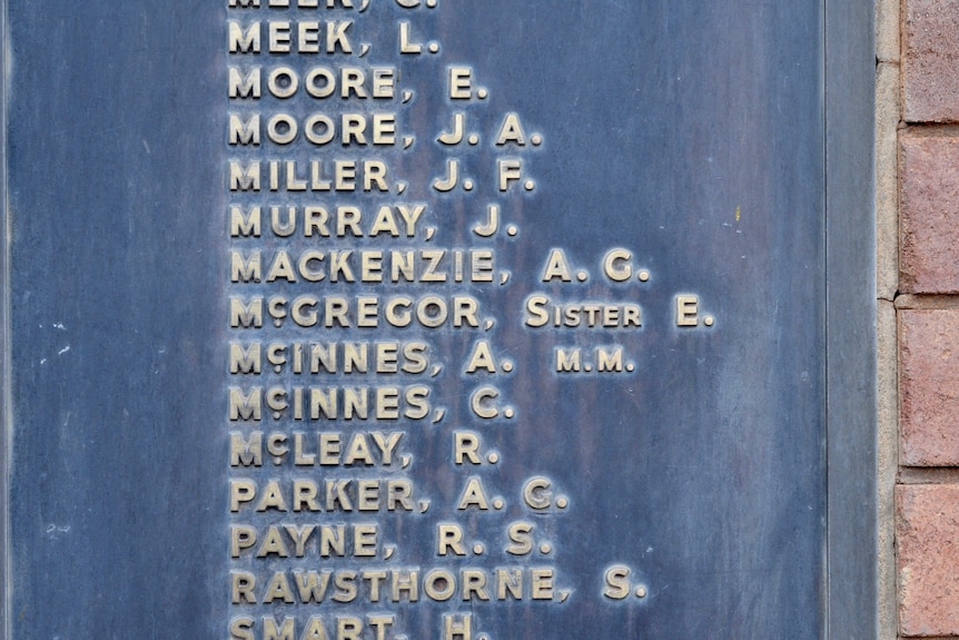 A brass plate with raised lettering of names.