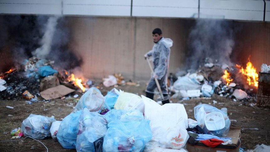 Man cleans rubbish in Turkish tent city