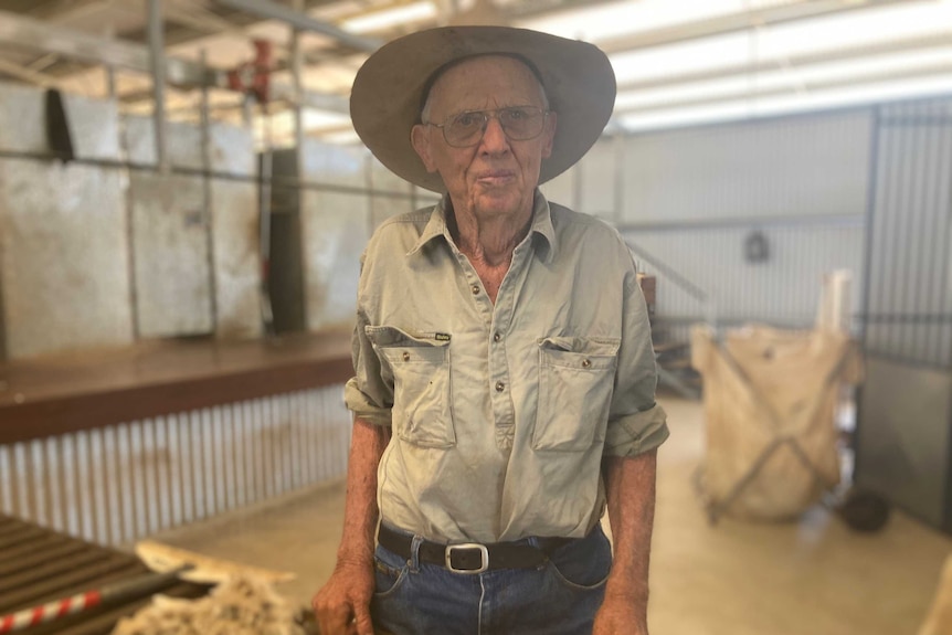 Wool grower Jim Counsell stand in front on a wool classing table in a shearing shed