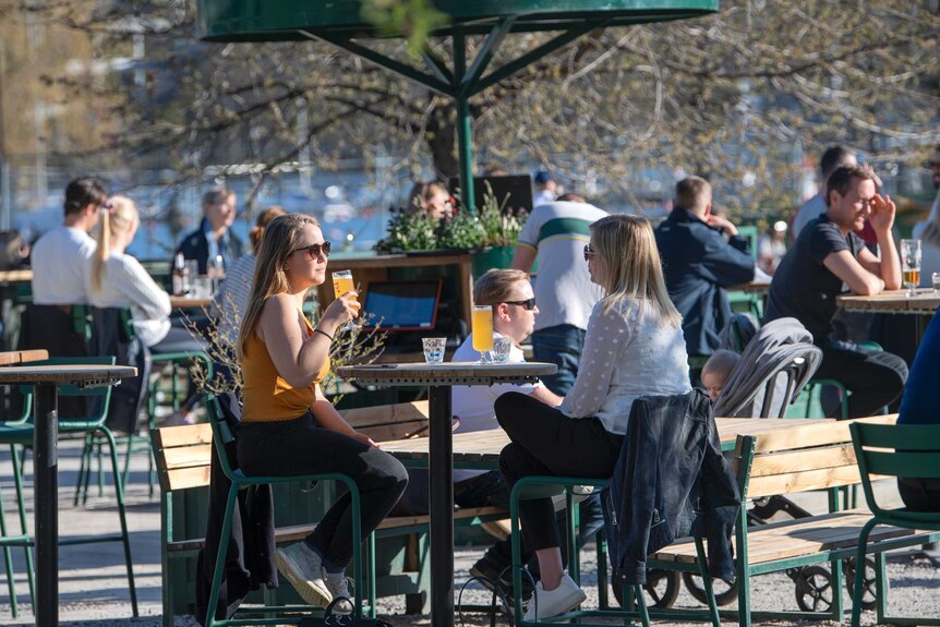 People gather for a drink at an outdoor bar in Stockholm, Sweden, despite coronavirus.