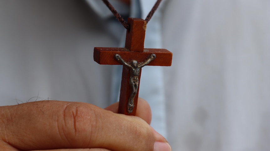 A wooden cross being held by a hand