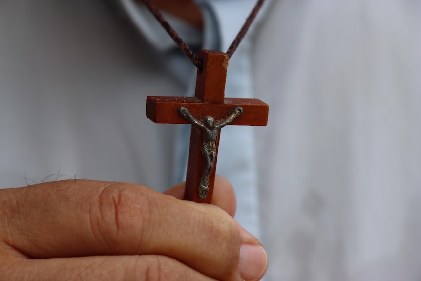 A wooden cross being held by a hand