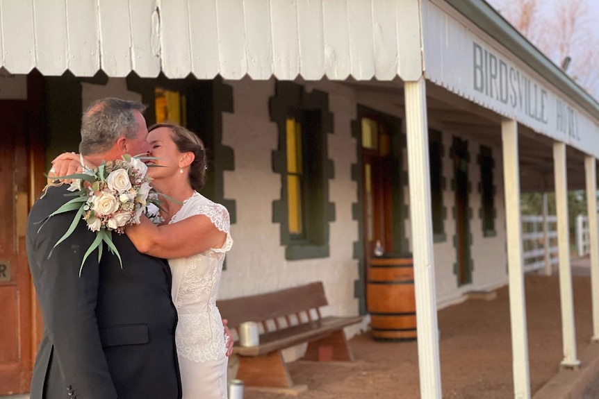 A man and lady kiss on their wedding day outside the Birdsville Hotel.