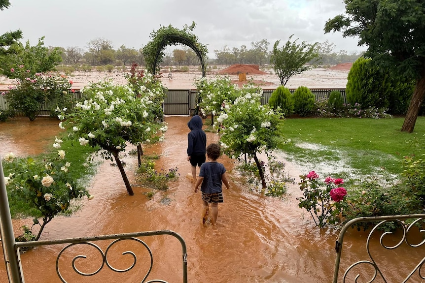 two young kids play in a flooded front garden