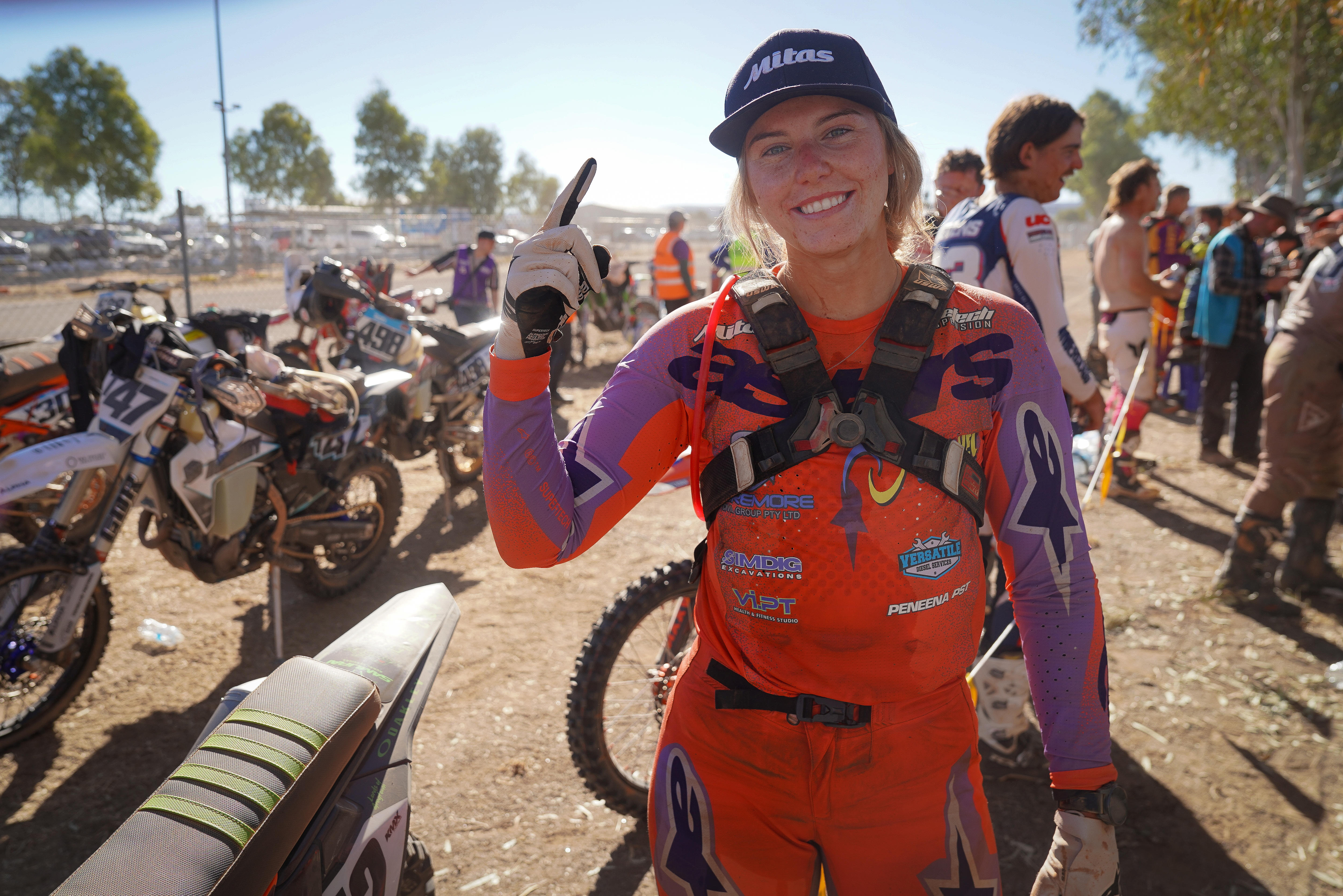 A woman in offroad motorcycle gear celebrates a win.