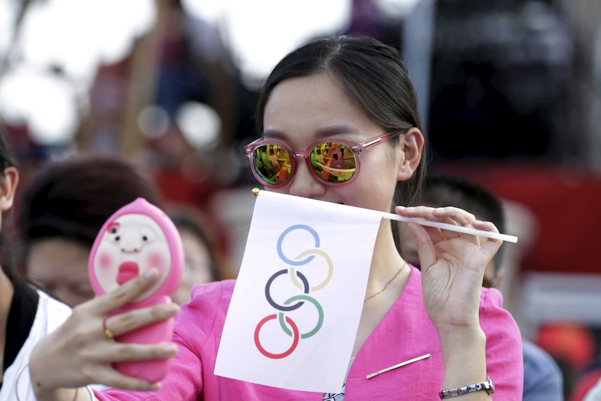 A local woman takes a selfie with an Olympics flag