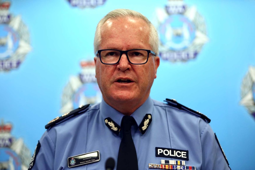 Chris Dawson standing in front of a WA Police background.
