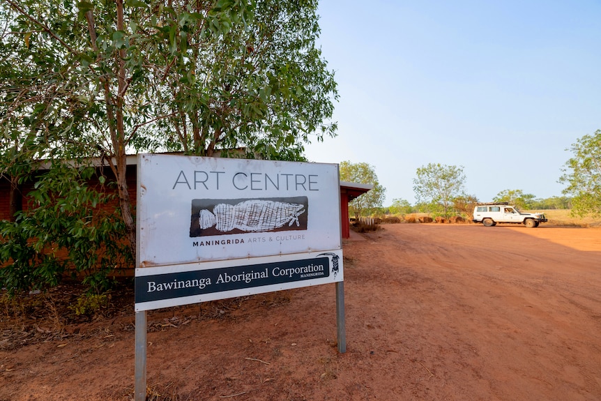 A sign outside a building that stands in red dirt, which reads "Arts Centre".