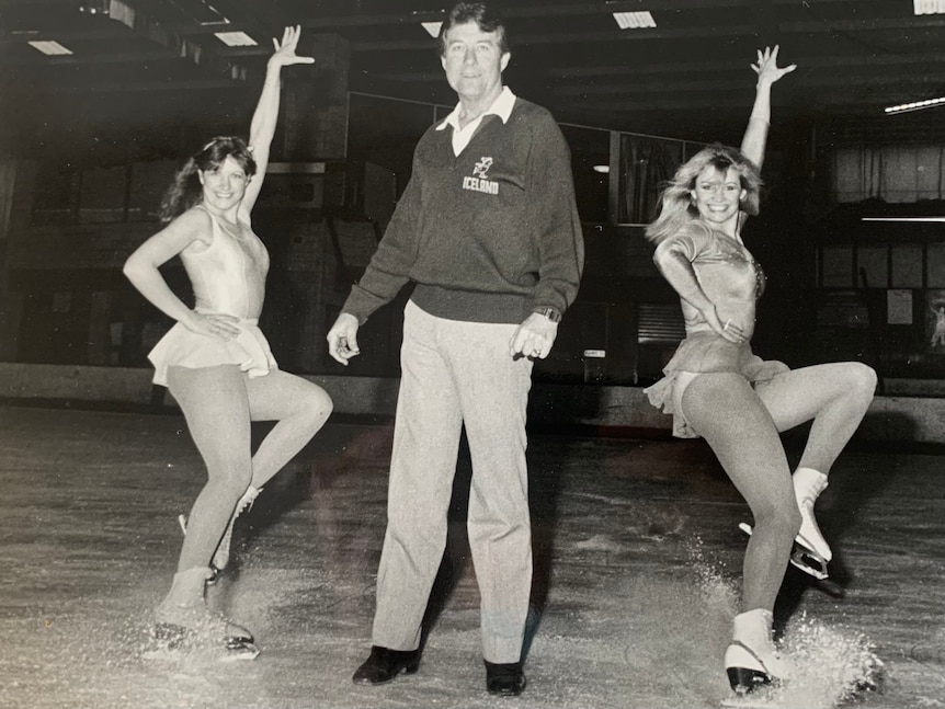 man and two ice skaters on ice rink